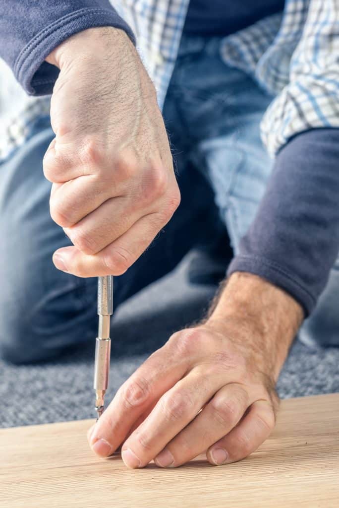 Man assembling furniture at home, hand with screwdriver